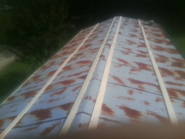 Rusted metal roof panels with new wood purlins before replacement — Storm Damage Roof Repair in Grainfield by Roofing Brothers