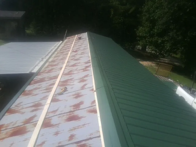 Old rusted panels beside newly installed green metal roofing — Wind Damage Roof Repair by Roofing Brothers in Grainfield