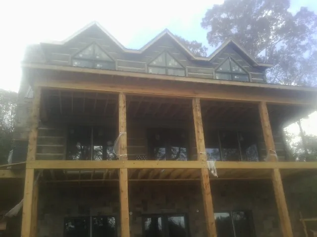 Dormers and porch framing on a large log home under construction — Roof Coating work by our crew in Grainfield