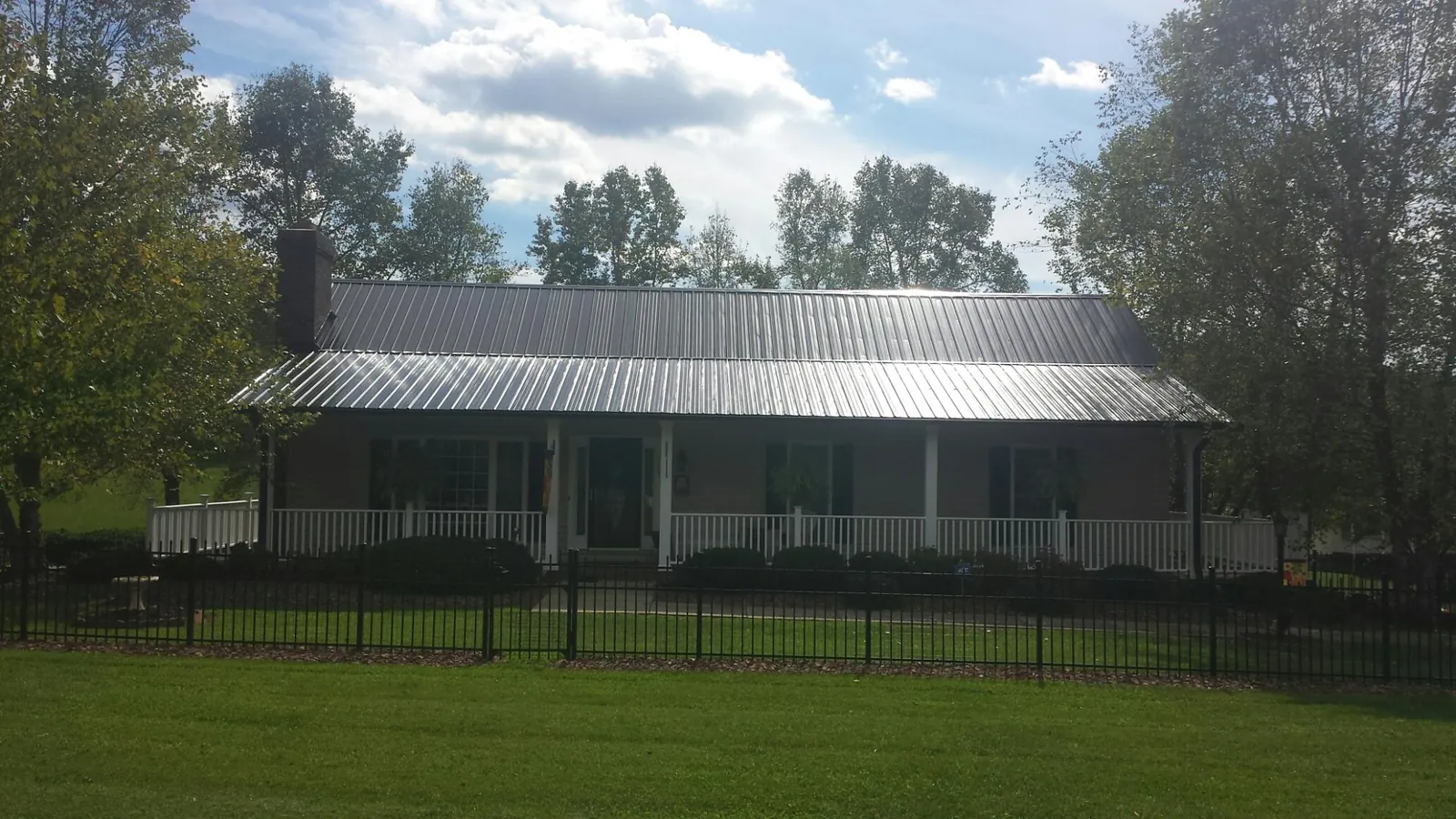 Gray metal roof on a brick ranch with a full width front porch — Gutter Guard Installation work by our crew in Grainfield