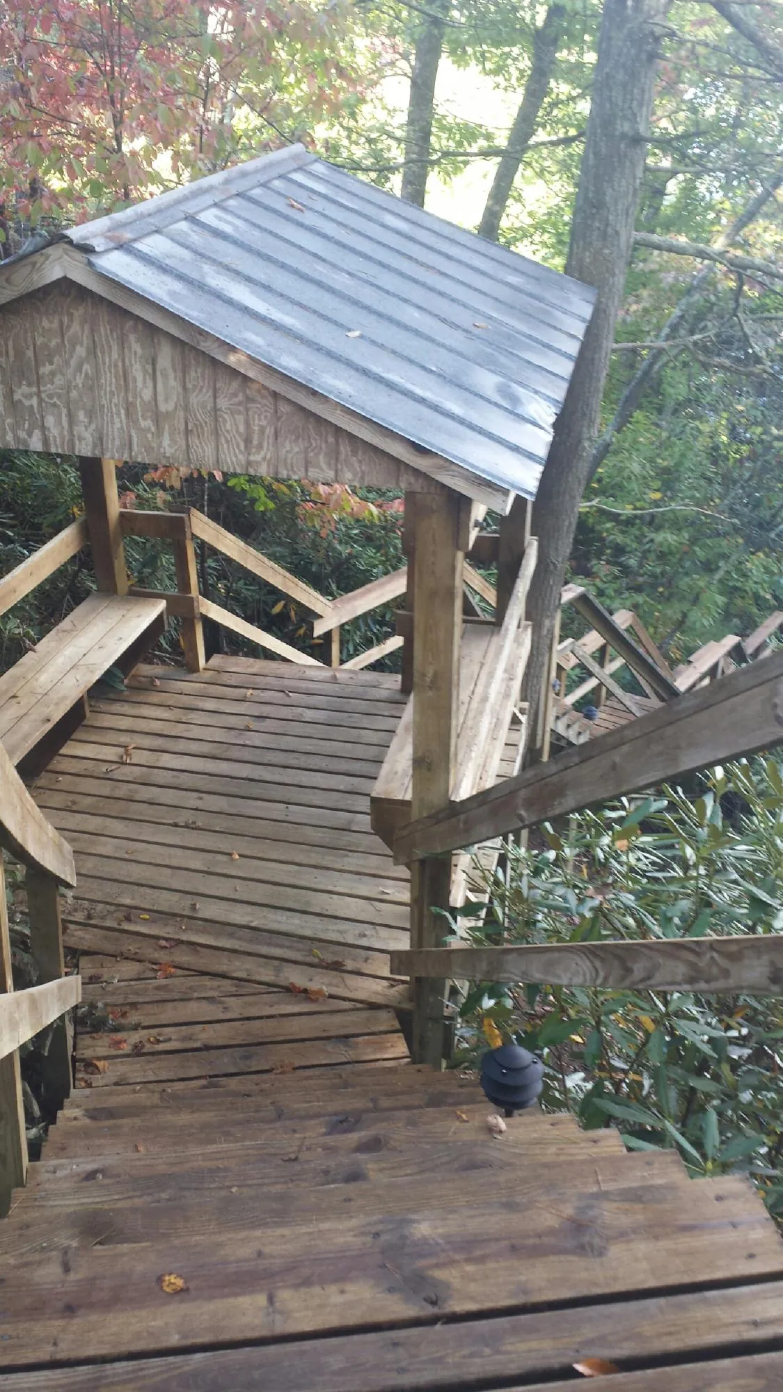 Metal roofed shelter over wooden steps on a wooded walkway — Skylight Repair & Installation work by our crew in Grainfield