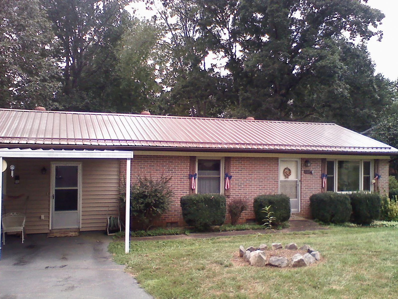 Bronze metal roof and carport on a brick ranch home — Roof Repair work by our crew in Grainfield